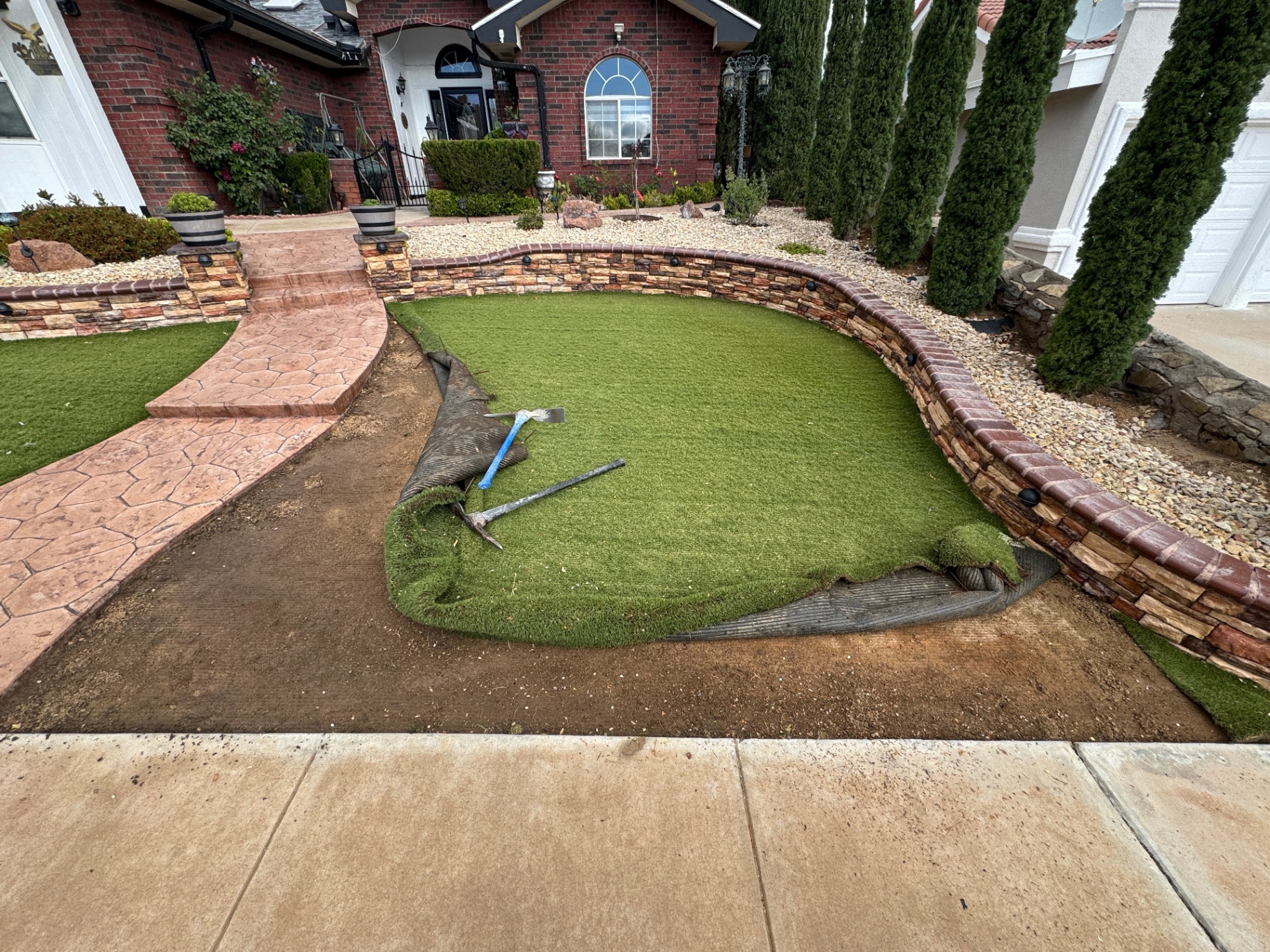 Turf being trimmed and shaped along the stone border at the James Dudley Dr install