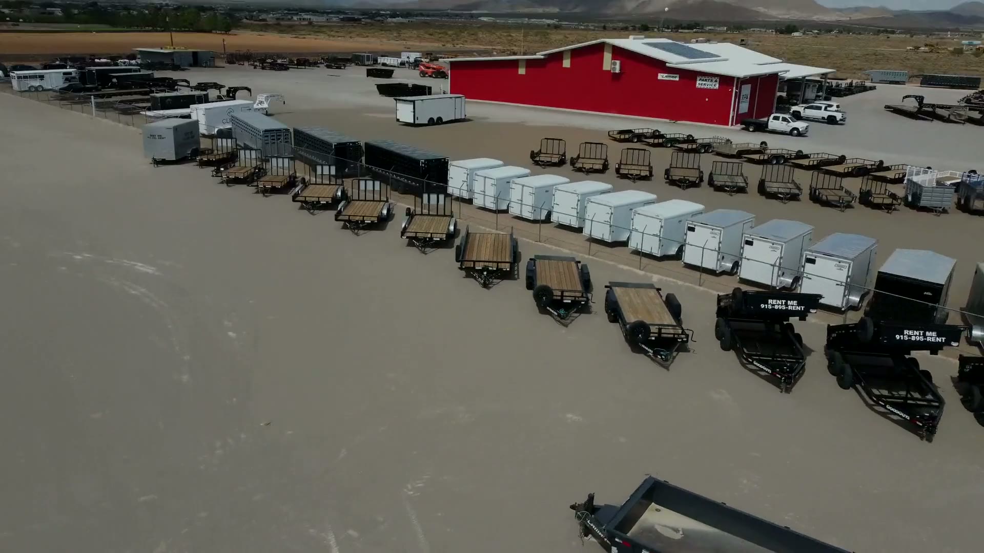 Aerial view of the EquipScape yard in El Paso — dump trailers, skid steers, bulk material piles and the rental building